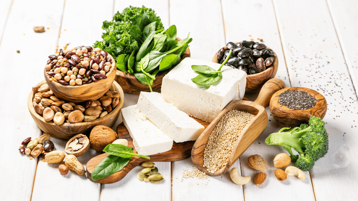 Selection of vegan plant protein sources - tofu, quinoa, spinach, broccoli, chia, nuts and seeds, wood background