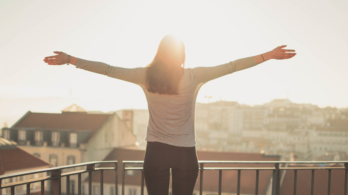 woman standing with arms open facing the sun